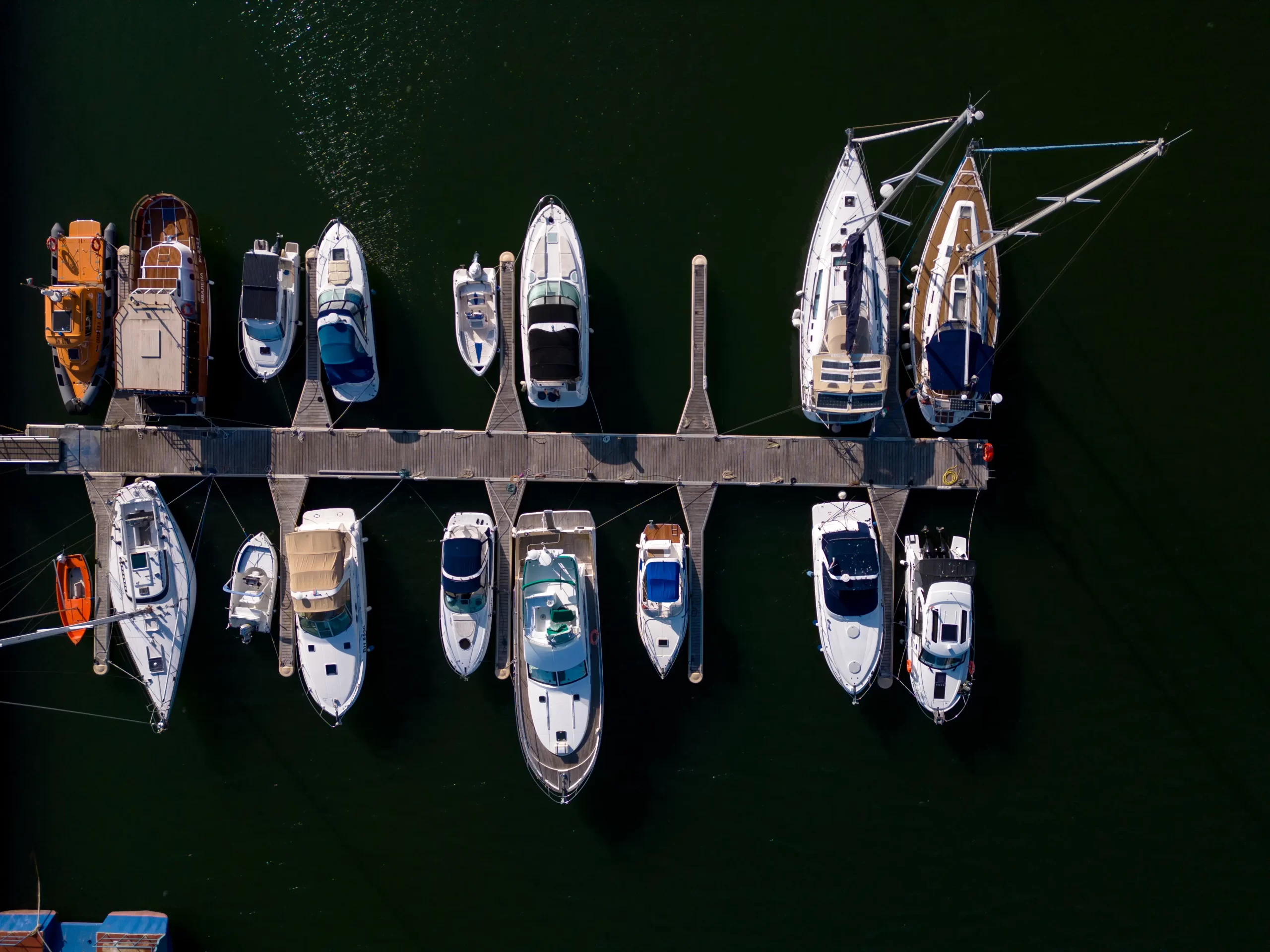 Aerial view of a yacht marina by the sea, adorned with elegant yachts, creating a picturesque maritime scene.